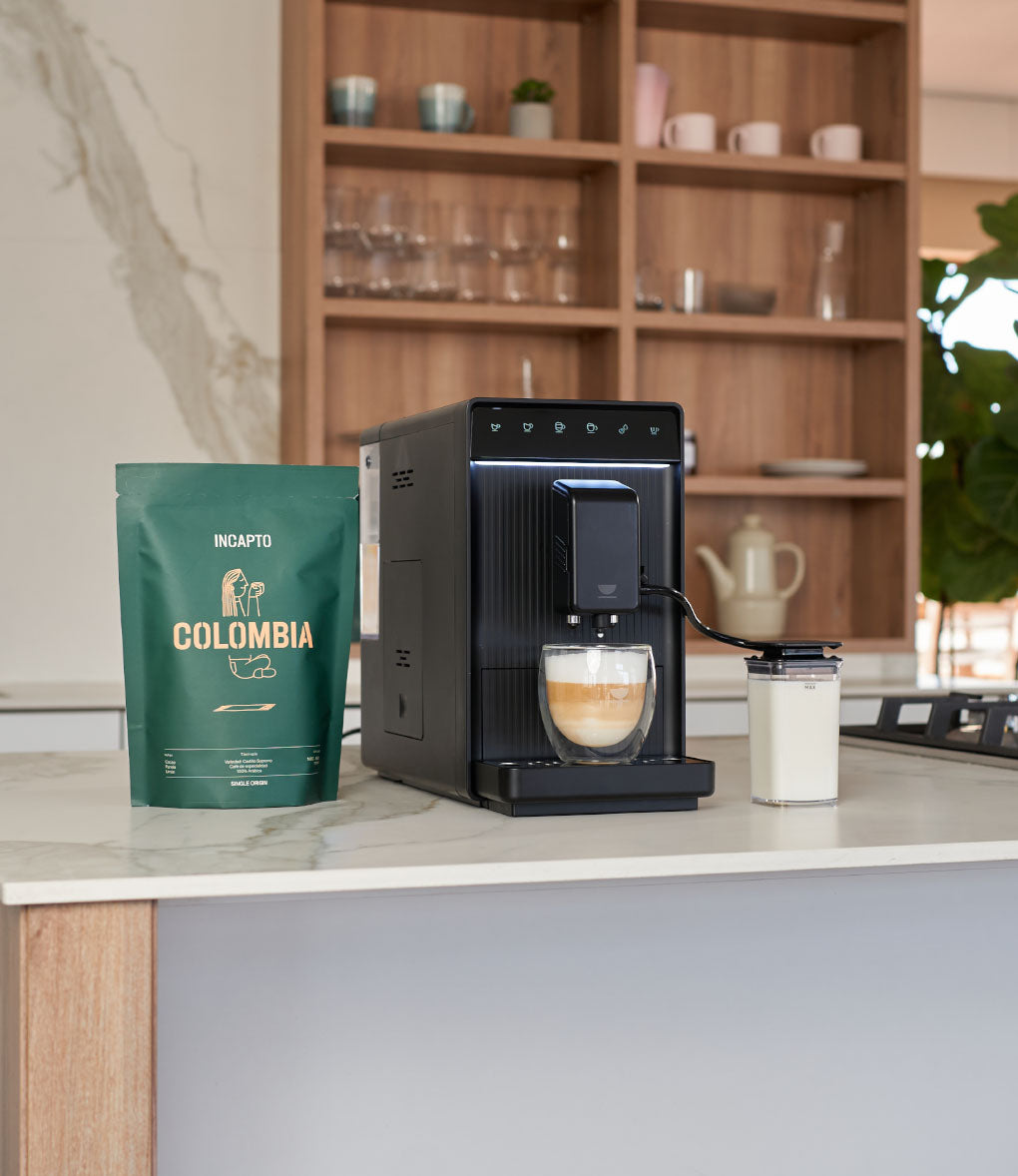 Cafetera INCAPTO Aura Milk con depósito de leche y pack de café sobre encimera de cocina