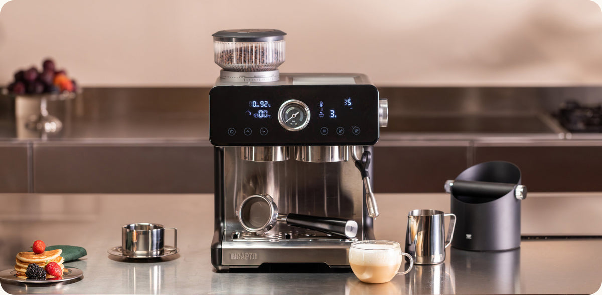 Cafetera INCAPTO Sabi en la encimera junto a un cappuccino recién hecho