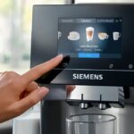 Mano di donna su schermo touch screen della macchina da caffè Siemens EQ700