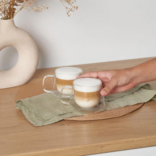 Tazas doble fondo cappuccino sobre encimera de cocina con mano