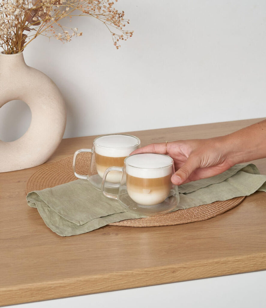 Tazas doble fondo cappuccino sobre encimera de cocina con mano